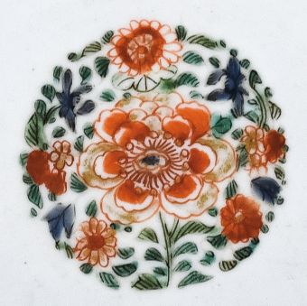 图为清代五彩花卉纹碟细节图，碟心主题纹饰为团花图，红花绿叶，相映成趣。（来源：广州十三行博物馆）